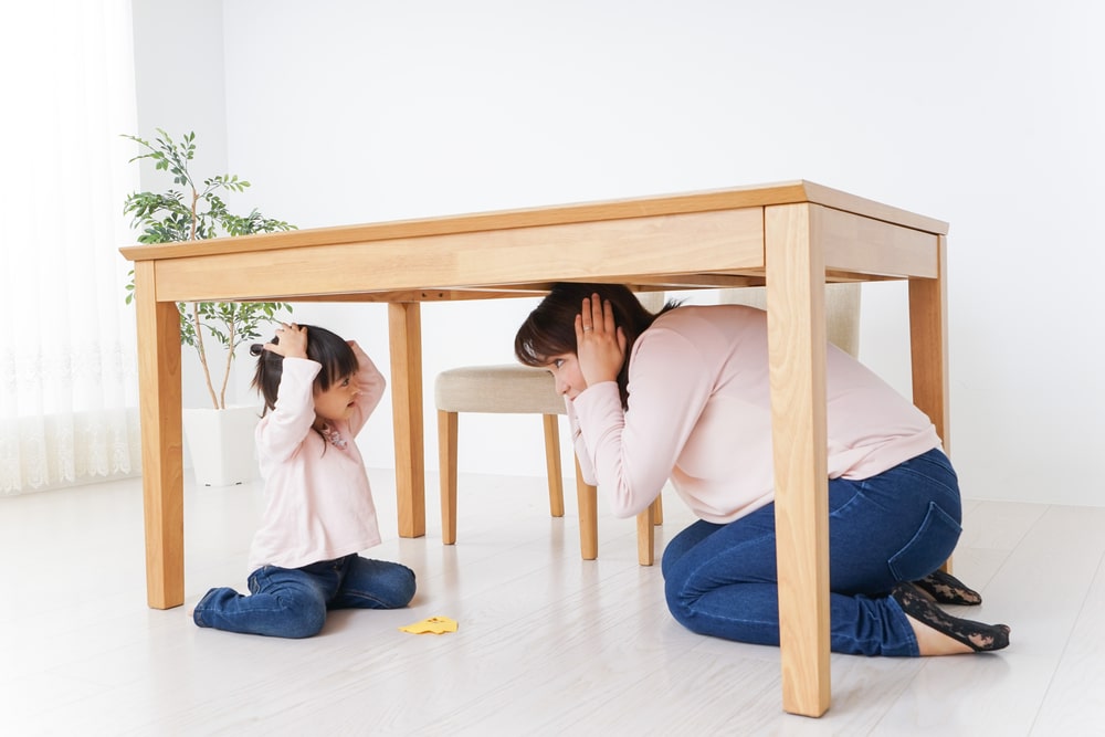Mom and child sheltering under table during earthquake